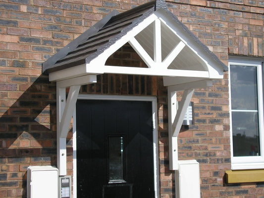 An over door canopy with a white base and a brown roof, installed above a door on a brick wall.
